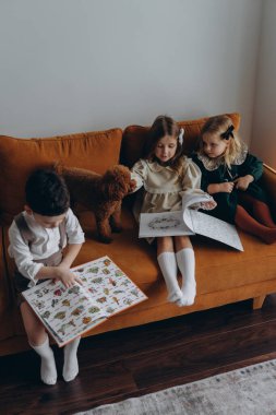 Bohem gibi giyinmiş güzel çocuklar Noel arifesinde kanepede oturup pencerenin yanında kitap okuyorlar.