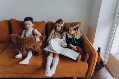 Bohem gibi giyinmiş güzel çocuklar Noel arifesinde kanepede oturup pencerenin yanında kitap okuyorlar.