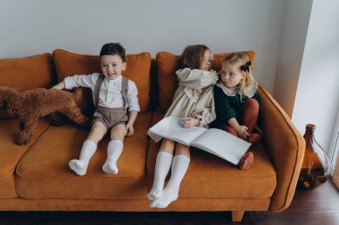 Bohem gibi giyinmiş güzel çocuklar Noel arifesinde kanepede oturup pencerenin yanında kitap okuyorlar.