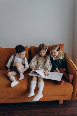 Bohem gibi giyinmiş güzel çocuklar Noel arifesinde kanepede oturup pencerenin yanında kitap okuyorlar.