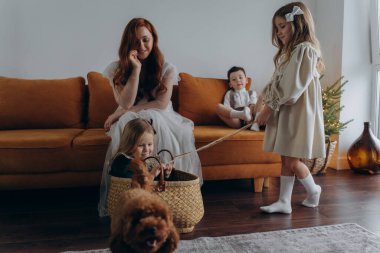 Kızları ve oğluyla birlikte beyaz bohem elbiseler giymiş güzel bir kızıl kadın Noel arifesinde birlikte vakit geçiriyorlar ve en küçük kız sepette oturuyor.