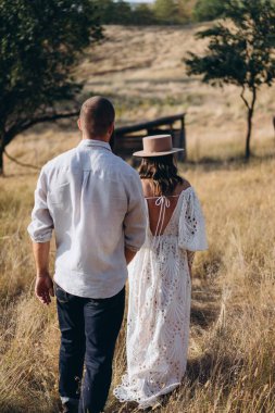 Kırsal kesimde güzel bir çift, arkadan bakınca beyaz elbiseli yakışıklı sakallı adam ve kadın. 