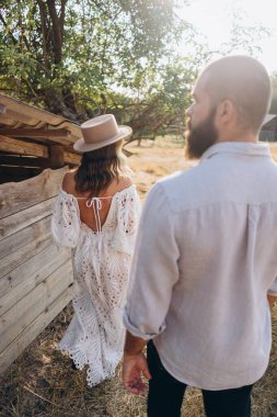 Kırsal kesimde güzel bir çift, arkadan bakınca beyaz elbiseli yakışıklı sakallı adam ve kadın. 