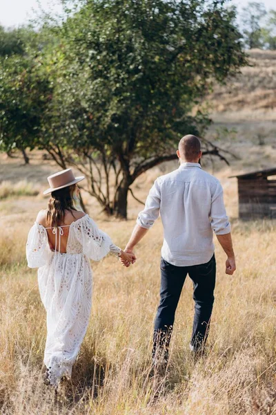 Beautiful couple at countryside, back view handsome bearded man and woman in white dress