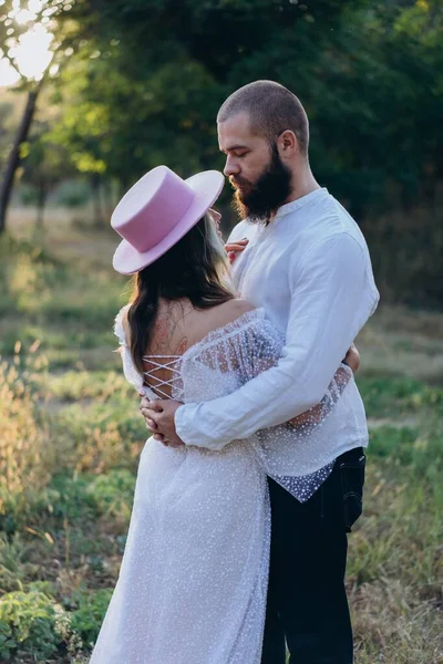 Beautiful couple at countryside, handsome bearded man hugging woman in white dress