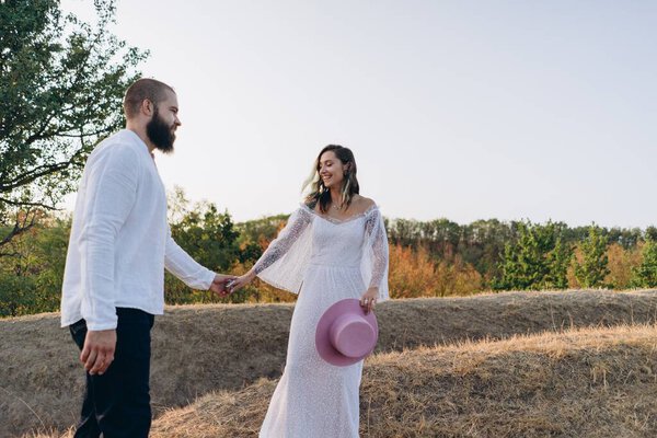 красивая пара в сельской местности, красивый бородатый мужчина и женщина в белом платье ходить и держаться за руки