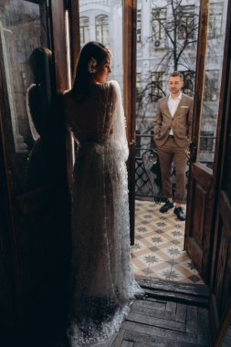 Zarif takım elbiseli bir adam balkonda sevgilisinin önünde duruyor ve balkonun kapısında duran güzel, beyaz, şehvetli bir tül elbise giymiş bir kız. 