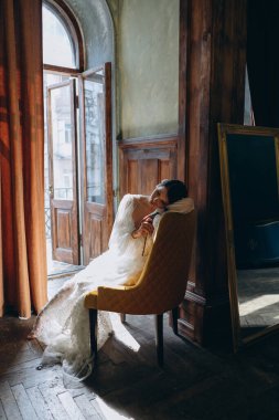  Balkonun yanındaki sandalyede oturan güzel, beyaz, bohem tül elbiseli bir kız. 