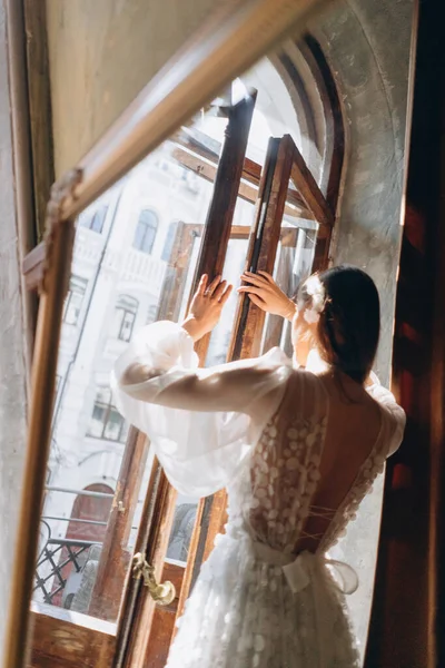 美しい白いボヘミアンチュールのドレスの女の子が彼女とバルコニーへの扉を開くカメラに戻る — ストック写真