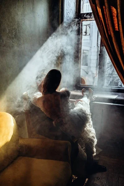Мужчина Элегантном Костюме Сидит Кресле Девушка Красивом Белом Чувственном Платье — стоковое фото