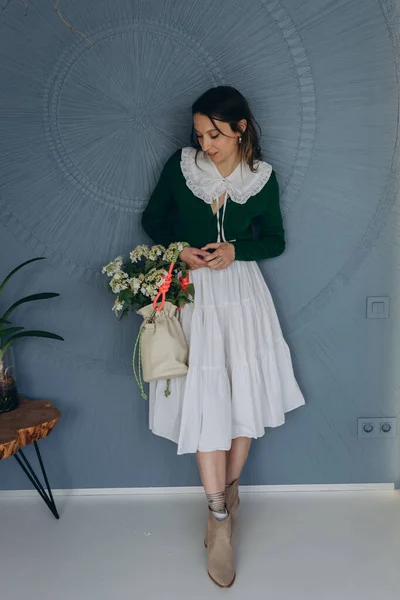 青い部屋に白いレースの襟付きの緑のヴィンテージドレスを着た美しい女性の写真と彼女の手の中に白い花を保持 — ストック写真