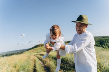  smiling father throwing up his happy daughter in the air 