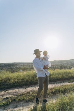  happy father holding his daughter and walking in the field