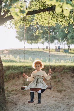 Tahta salıncakta sallanan güzel kızıl saçlı kız.