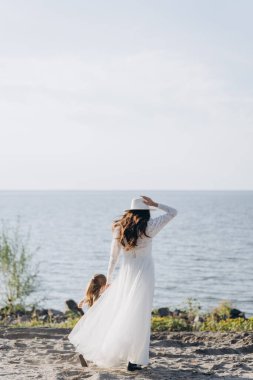 Anne ve küçük kızın ormanın yakınındaki nehir kıyısında birlikte vakit geçirdikleri güzel fotoğraf.