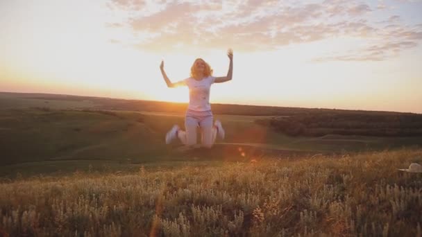 Meisje springen op de achtergrond van de zonsondergang. buitenshuis — Stockvideo