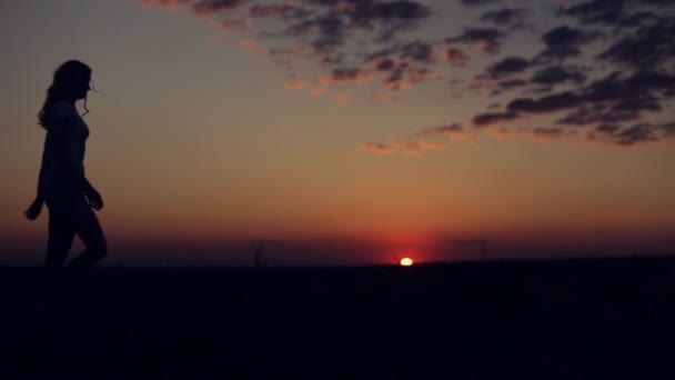 Silhouet van het meisje lopen op zonsondergang achtergrond — Stockvideo