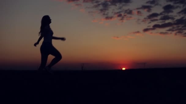 Σιλουέτα του κοριτσιού να τρέξει και να πηδήξει σε φόντο ηλιοβασίλεμα — Αρχείο Βίντεο