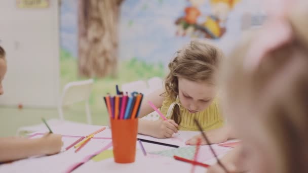 Klein meisje tekening met gekleurde potloden op papier — Stockvideo