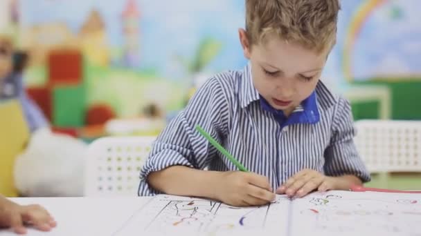 Jongetje tekenen met kleurpotloden op papier — Stockvideo