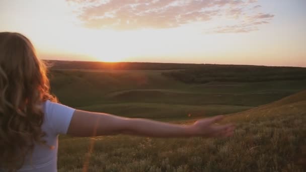 Женщина с распростертыми объятиями под восходом солнца на поле — стоковое видео