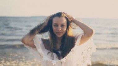 Sahilde gülümseyen kız ve saç düzeltiyor