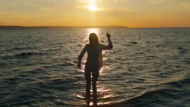 Meisje dansen in de zee in de zonsondergang — Stockvideo