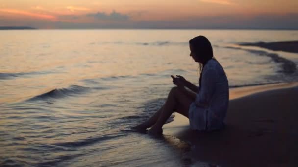 Meisje met een smartphone op strand bij nacht — Stockvideo