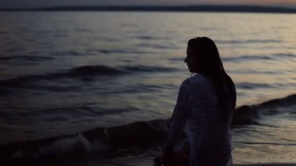 Menina sentada na praia à noite — Vídeo de Stock