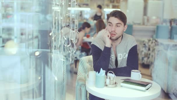 Jeune homme parlant sur un téléphone portable dans un café — Video