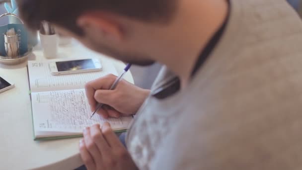 Jonge man schrijven in Kladblok in café — Stockvideo