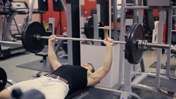 Člověk dělá bench pressu trénink v tělocvičně zpomalené — Stock video