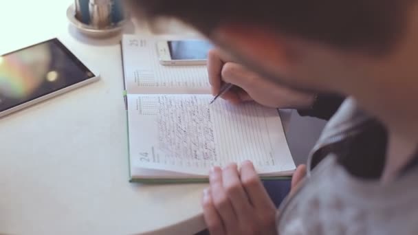 Jonge man schrijven in Kladblok in café — Stockvideo