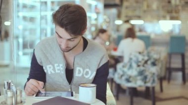 Tablet bilgisayar kafede oturan genç adam