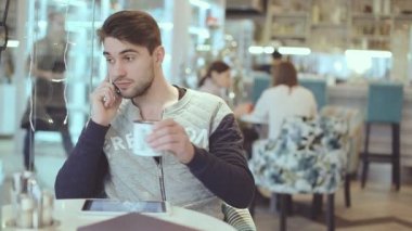 Kafede cep telefonuyla konuşan genç adam