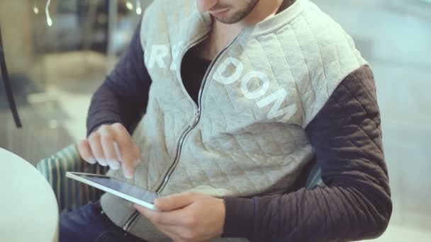 Jongeman met tablet pc zitten in Cafe — Stockvideo