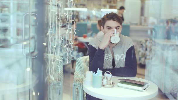 Mann trinkt Kaffee und blickt in Café in die Kamera — Stockvideo