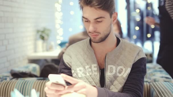 Junger Mann mit Smartphone sitzt im Café, Nahaufnahme — Stockvideo