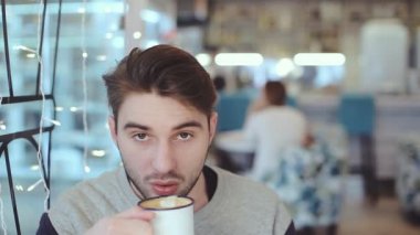 Genç adam kamera ve içecek kahve Cafe bakarak