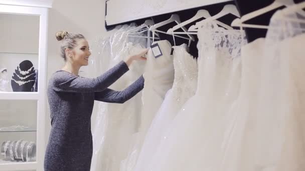 Jovem mulher escolhe vestido de casamento na boutique nupcial — Vídeo de Stock