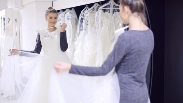 Девушка в свадебном платье щеголяет перед зеркалом — стоковое видео
