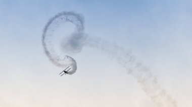 Eski bir çift kanatlı uçağın dumanlı akrobatik gösterisi