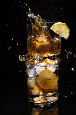 Viski duran bir bardak buz ve limon dilim tam üzerinde bir yüksek kaliteli cam düşen parça.