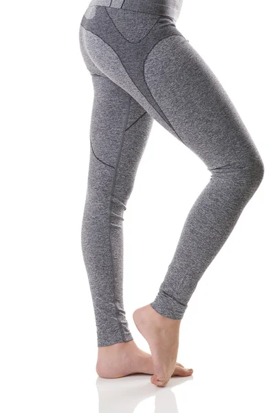 Nära håll Sidovy av kvinnan ben stretching musklerna i foten i grå sport thermo-underkläder med mönster. — Stockfoto