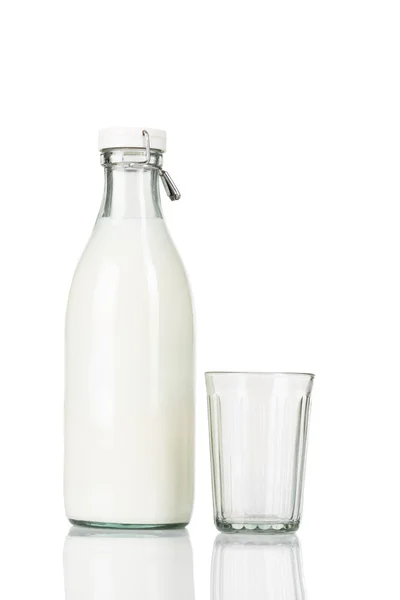 Empty faceted glass stands near a traditional closed old fashioned bottle of milk. — Stock Photo, Image