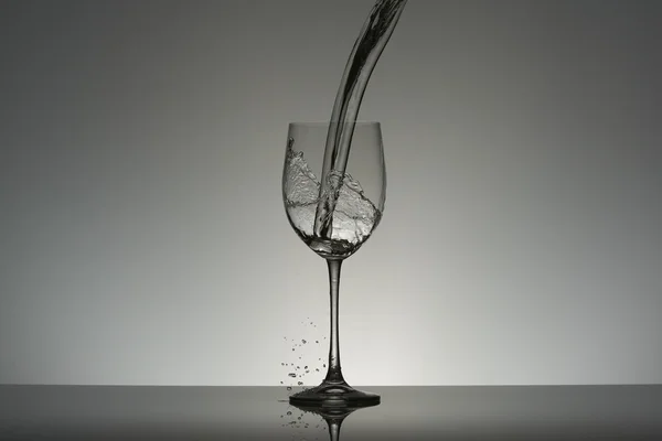 Caída de flujo de agua en una copa de vino . — Foto de Stock