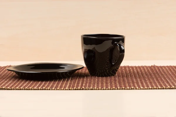 Taza de té negro de pie cerca de plato negro en tablemat . —  Fotos de Stock