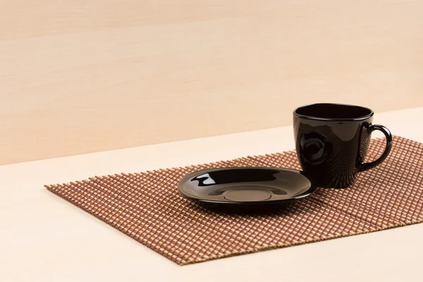 Placa negra de pie cerca de la taza de té negro en tablemat . —  Fotos de Stock