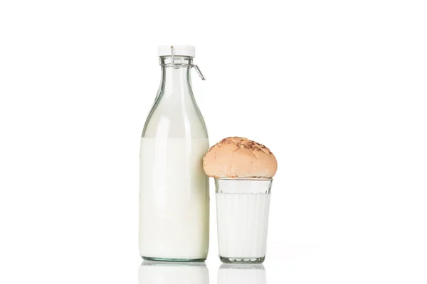 Vidro facetado de leite com um pão fica perto de garrafa de leite à moda antiga fechada . — Fotografia de Stock