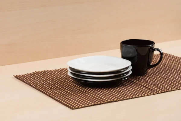 Pila de los platos blancos y negros cerca de la taza negra en la tabla . —  Fotos de Stock